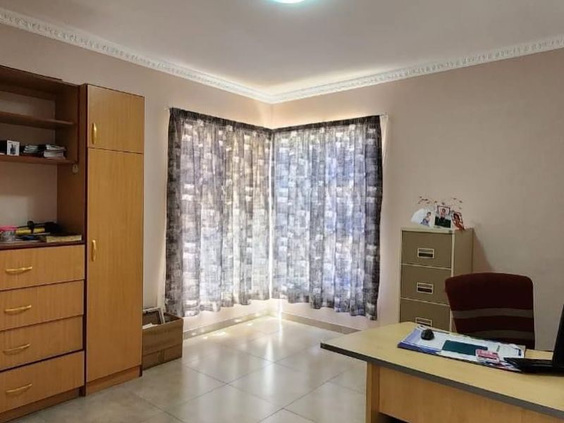 A functional home office space featuring tiled flooring, decorative ceiling cornicing, and ample natural light from the corner window arrangement.