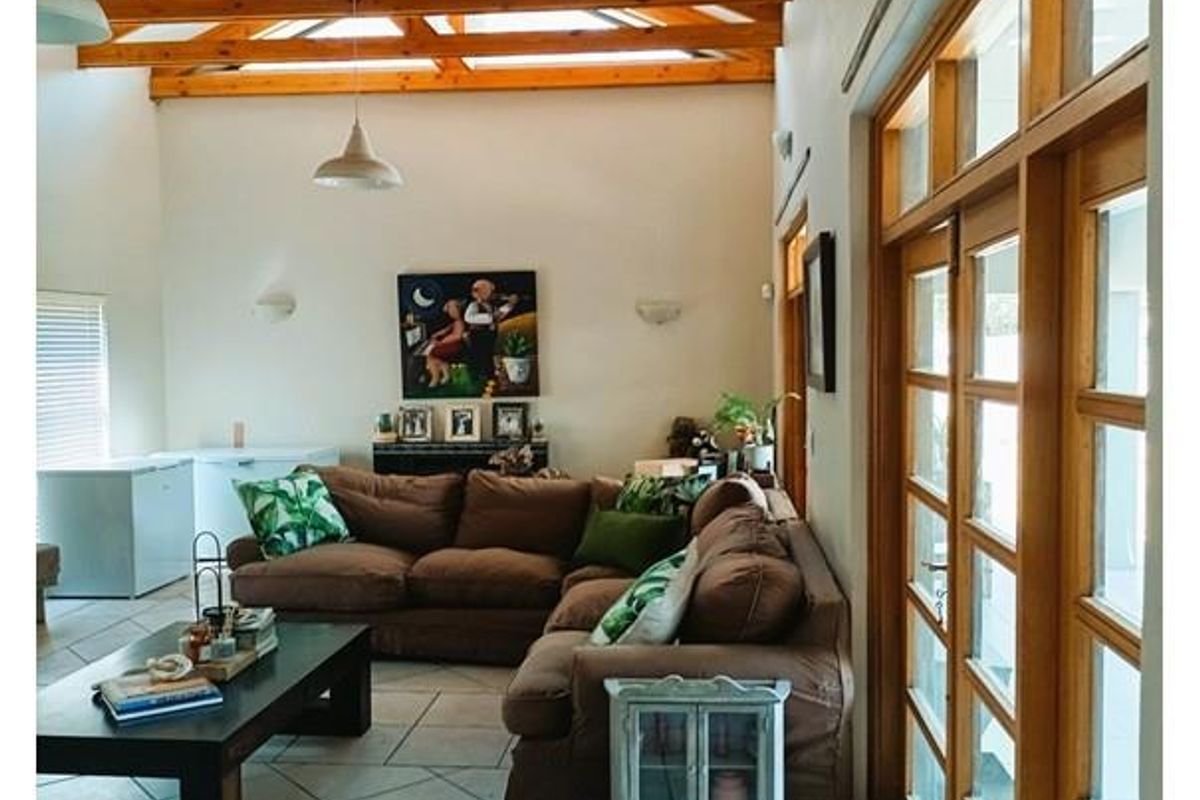Spacious living area featuring high vaulted timber beam ceilings, tiled flooring, and large wooden-framed glass doors providing ample natural light.