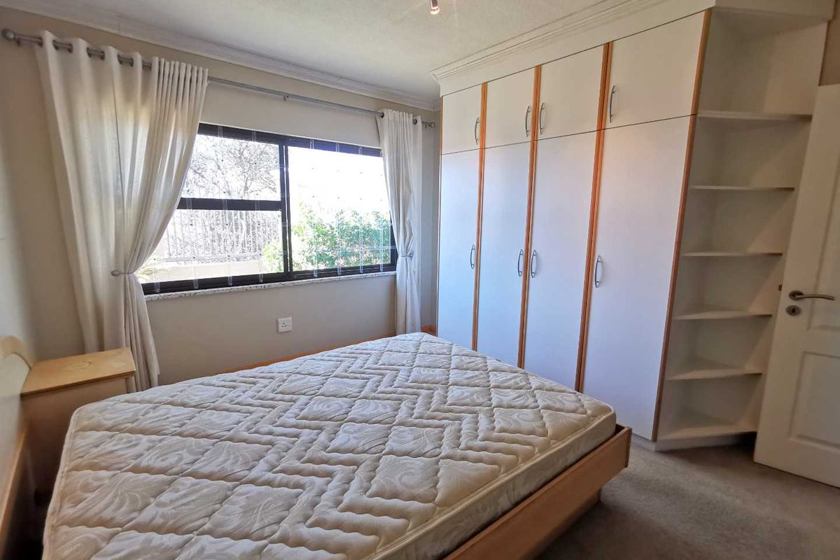 A bedroom featuring built-in floor-to-ceiling wardrobes with integrated shelving and a large window providing natural light.