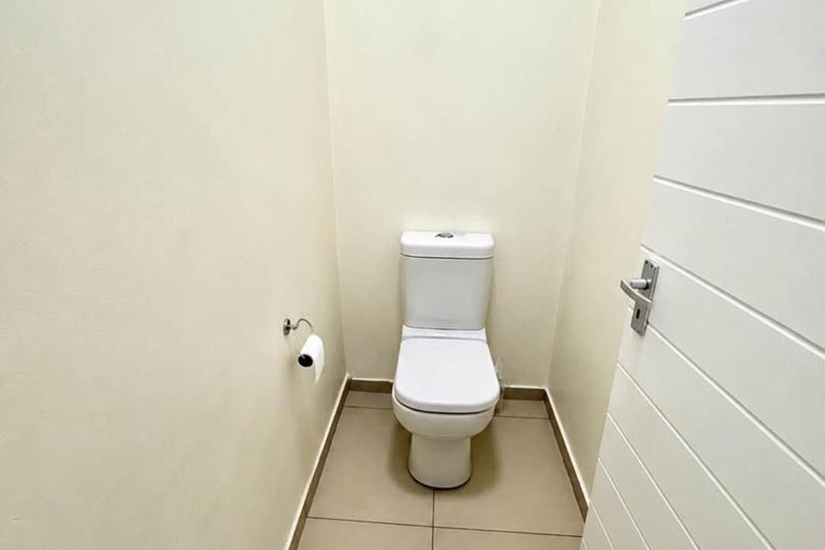 A clean and minimalist guest toilet featuring neutral floor tiles and a modern white toilet suite.