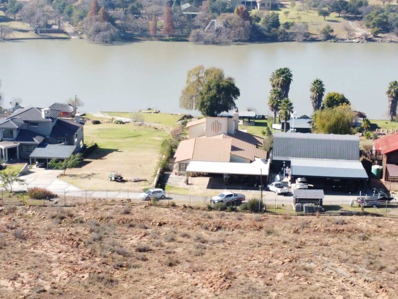Aerial view of waterfront residential properties featuring multiple dwellings, expansive lawns, and direct access to the riverbank.