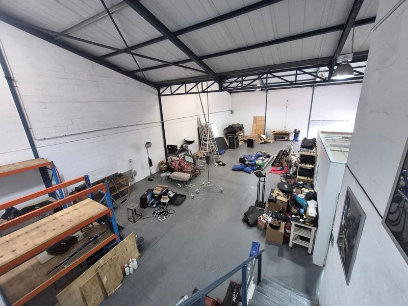 Spacious industrial warehouse unit featuring high ceilings with exposed steel trusses, concrete flooring, and functional open-plan layout suitable for storage or workshop use.
