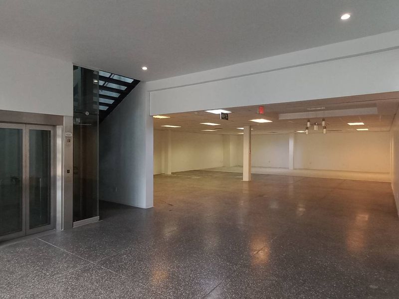 Spacious open-plan office area featuring polished concrete floors, a modern elevator, and integrated staircase access, offering a clean and versatile professional workspace.