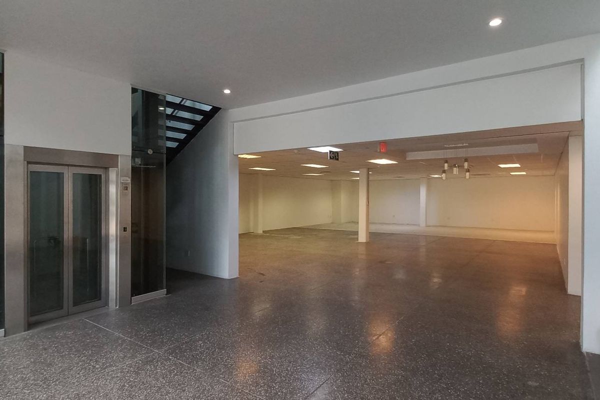 Spacious open-plan office area featuring polished concrete floors, a modern elevator, and integrated staircase access, offering a clean and versatile professional workspace.