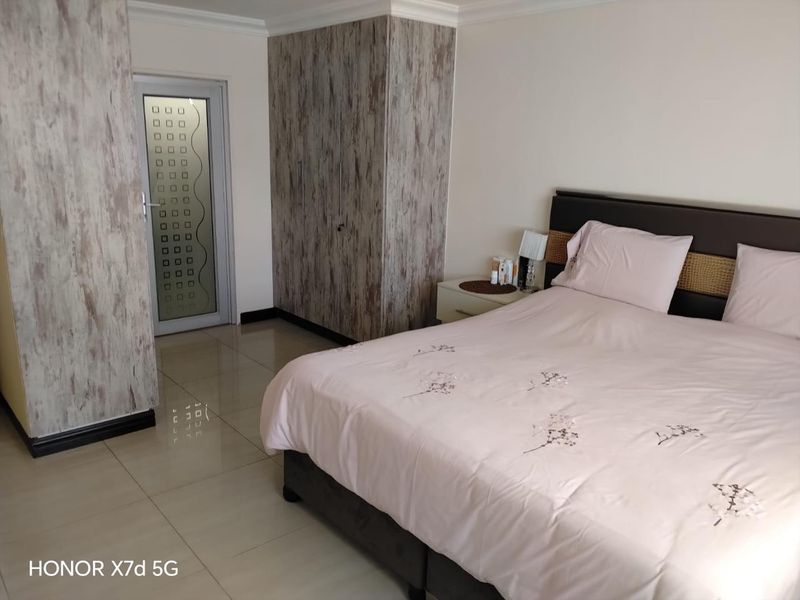A bedroom featuring tiled flooring, built-in cupboards with a textured finish, and a frosted glass door.