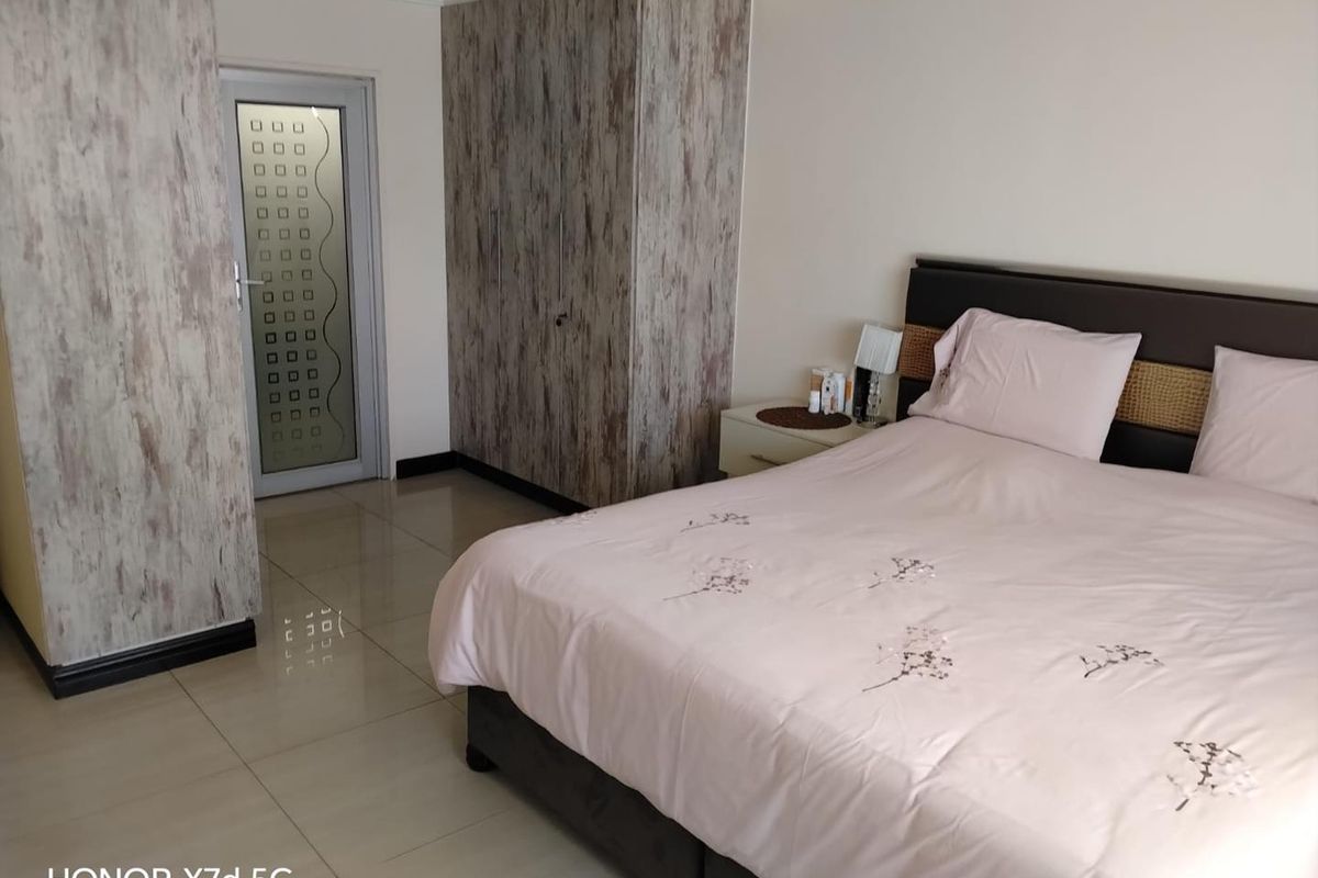 A bedroom featuring tiled flooring, built-in cupboards with a textured finish, and a frosted glass door.