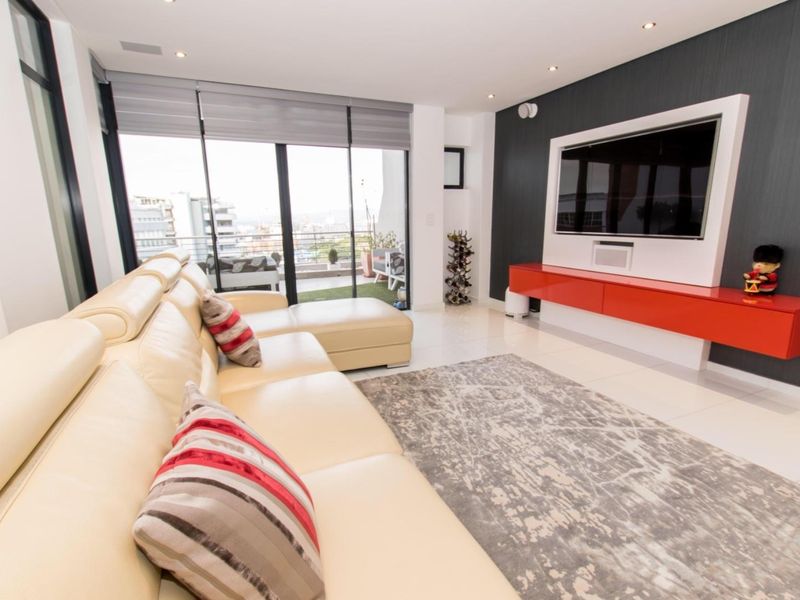 Modern living room featuring tiled flooring, a built-in media console, and large sliding glass doors leading to a balcony with city views.