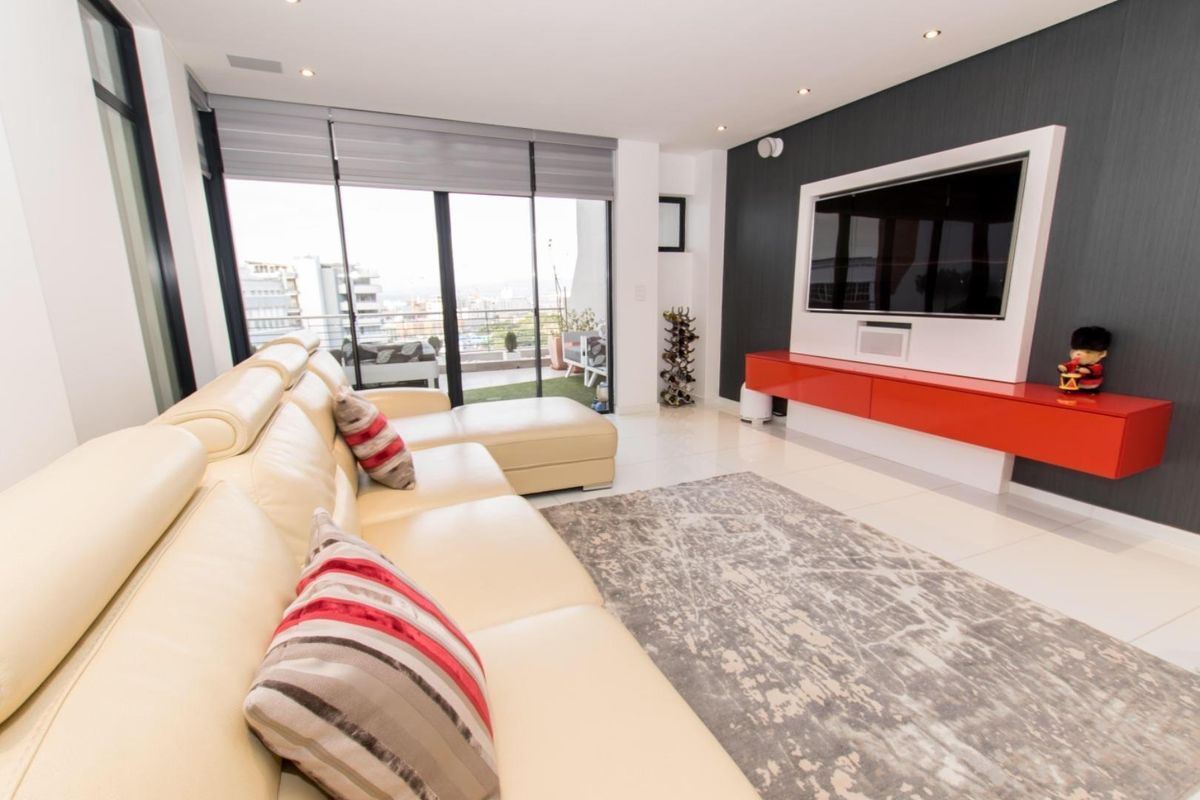 Modern living room featuring tiled flooring, a built-in media console, and large sliding glass doors leading to a balcony with city views.