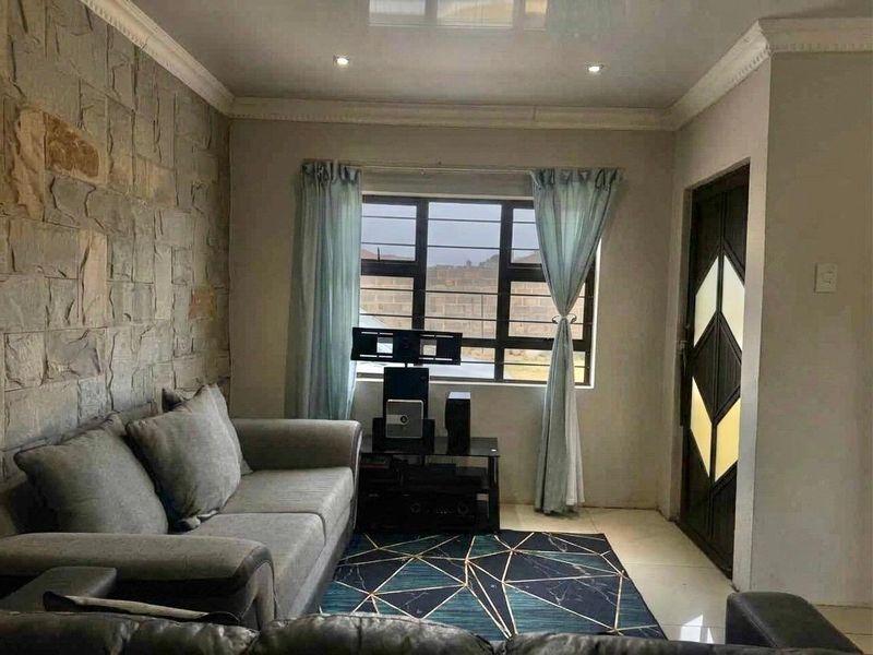 A living room featuring a textured stone accent wall, tiled flooring, recessed lighting, and a decorative entrance door with security window bars.