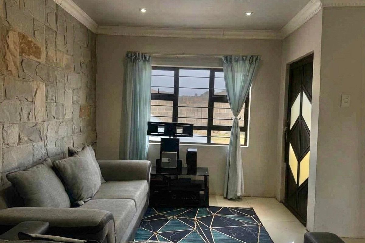 A living room featuring a textured stone accent wall, tiled flooring, recessed lighting, and a decorative entrance door with security window bars.