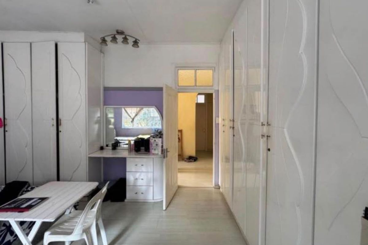 Bedroom featuring extensive white built-in cupboards and a matching built-in vanity unit with laminate flooring.