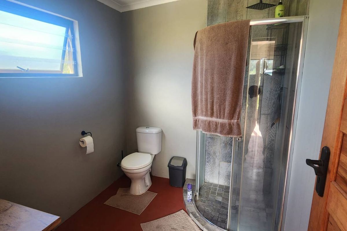 A functional bathroom featuring a corner shower enclosure, a standard toilet, and a vessel sink mounted on a wooden vanity.