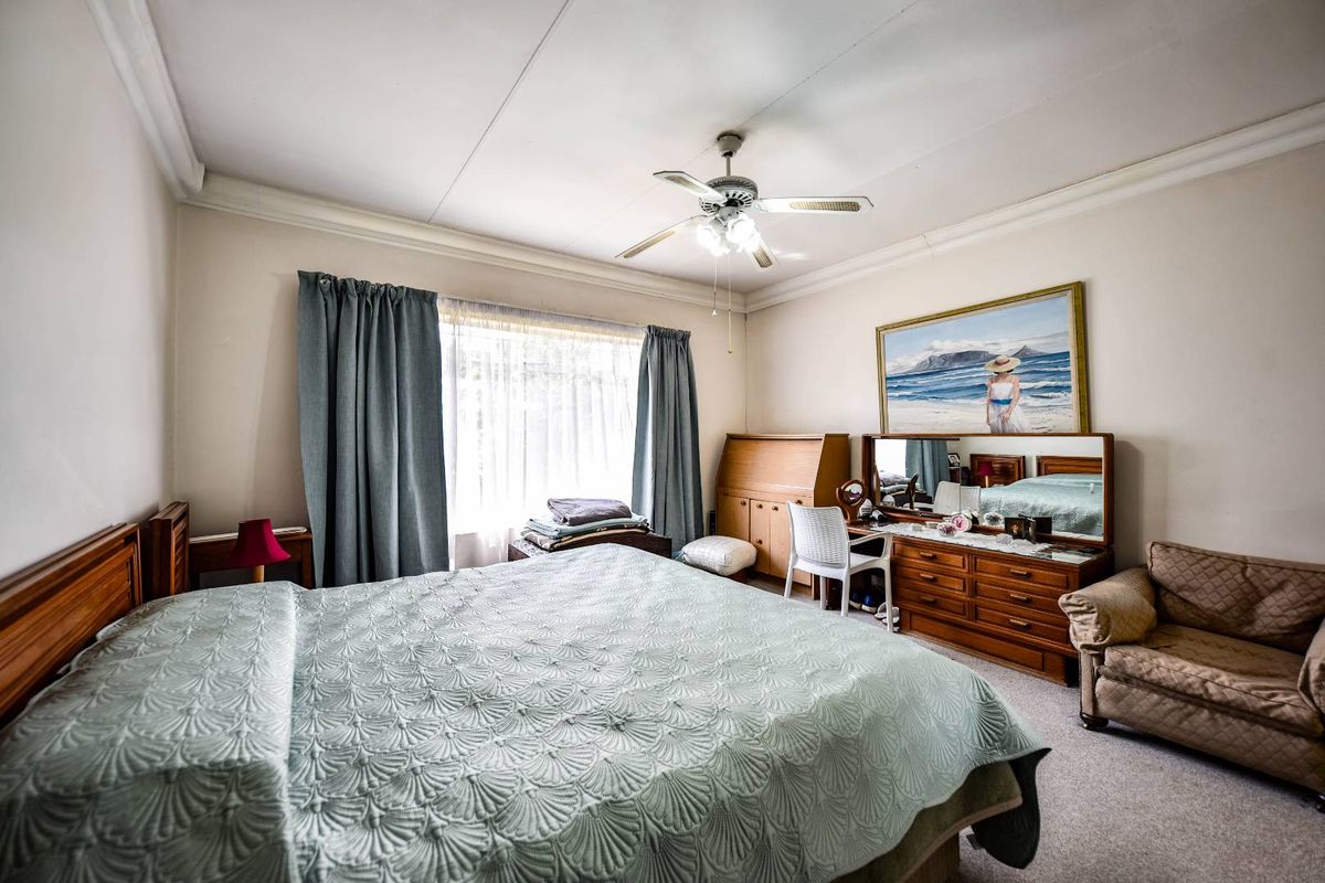 A spacious bedroom featuring a ceiling fan, neutral wall finishes, and carpeted flooring, offering a comfortable and functional living space.