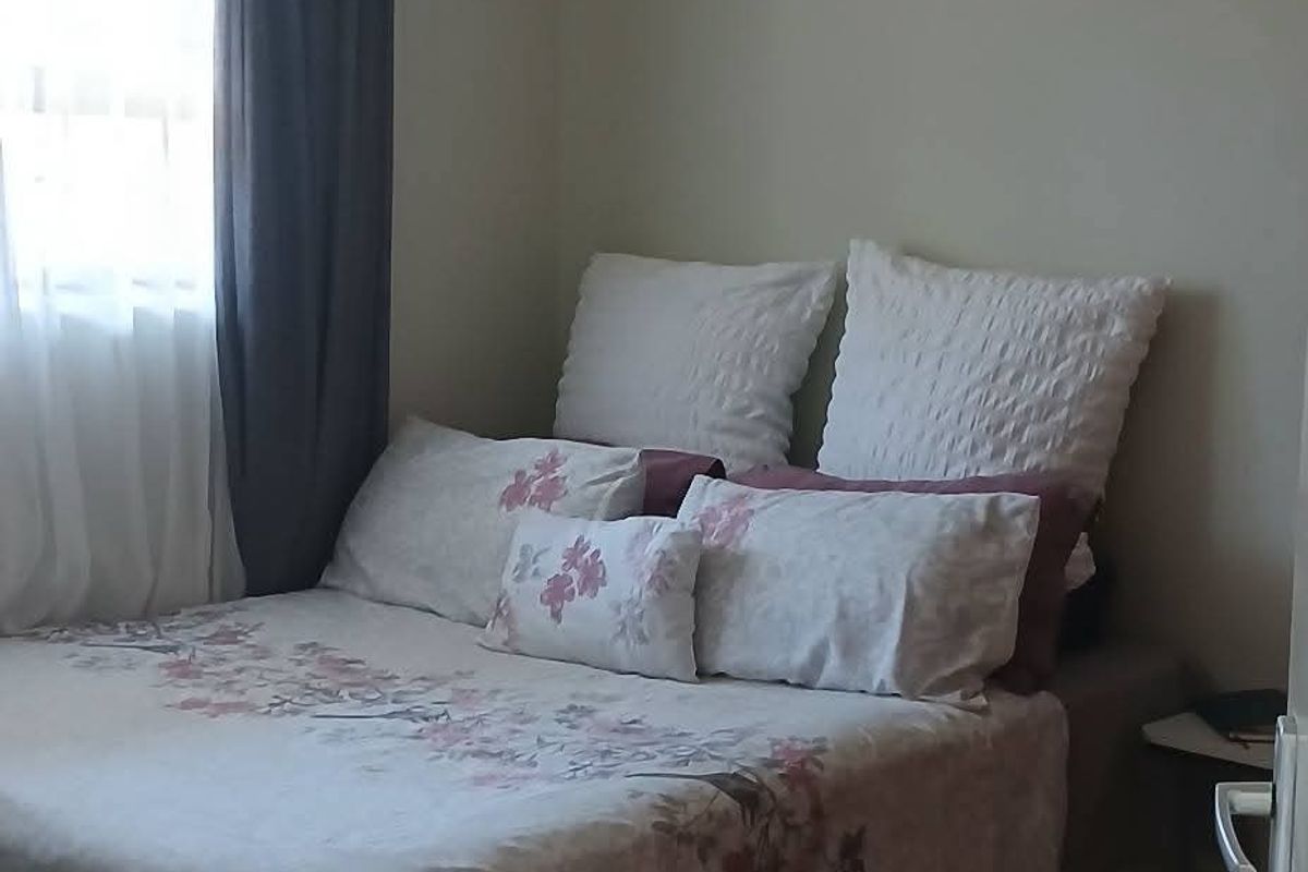 A compact bedroom featuring tiled flooring and a standard ceiling light fixture, providing a functional sleeping space.