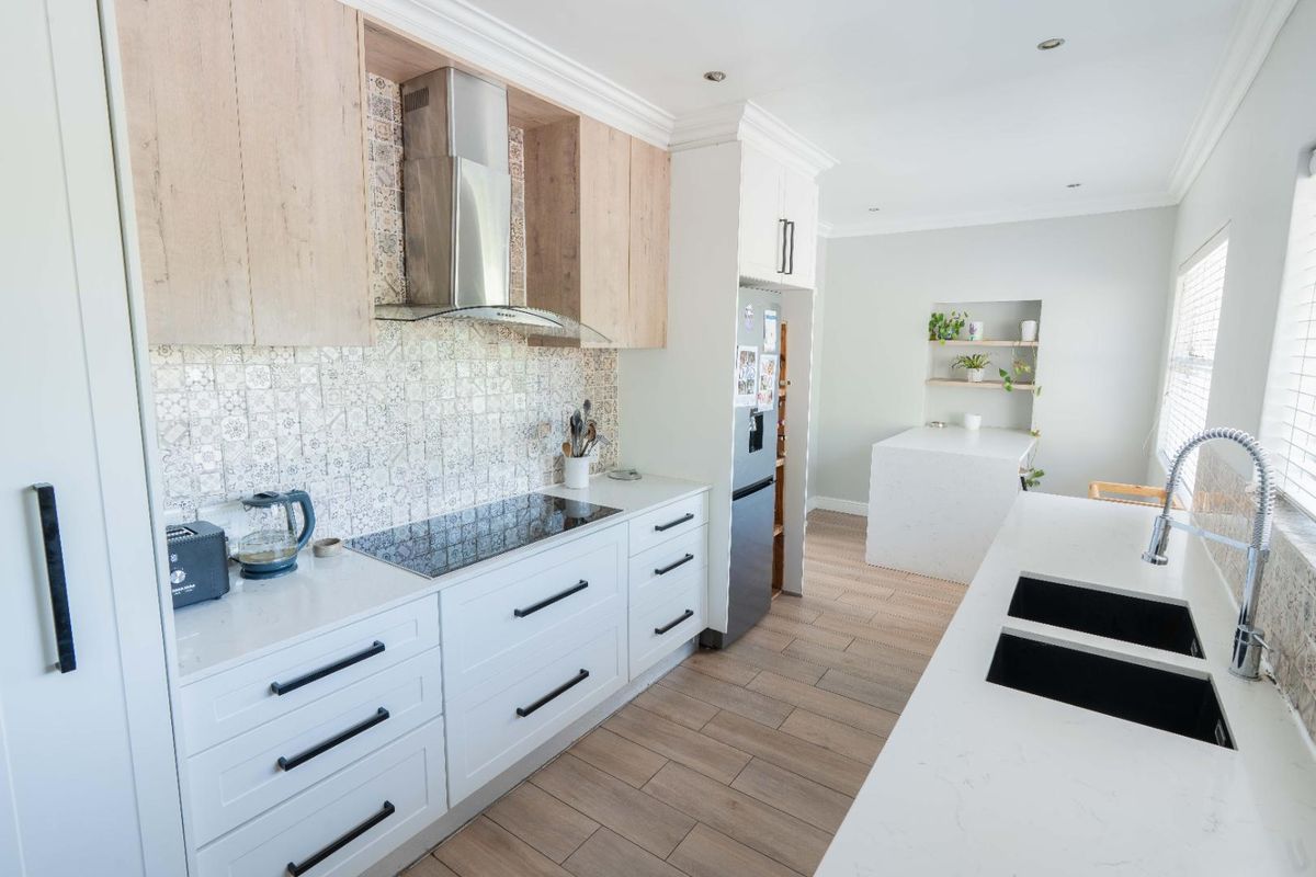 Modern kitchen featuring light wood and white cabinetry, stone countertops, induction hob, extractor fan, and a double undermount sink with a gooseneck faucet.