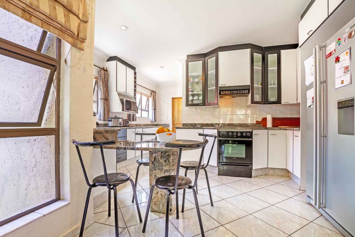 A functional kitchen featuring granite countertops, built-in cabinetry, a freestanding oven with extractor fan, and an integrated breakfast nook area.