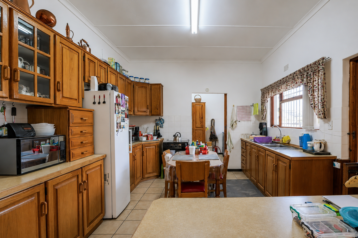 A functional kitchen featuring extensive wooden cabinetry, tiled flooring, and a dedicated dining area, offering a traditional layout with ample storage space.