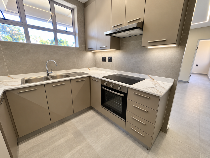 Modern kitchen featuring sleek taupe cabinetry, marble-effect stone countertops, integrated electric hob, oven, extractor fan, and high-quality tiled finishes.