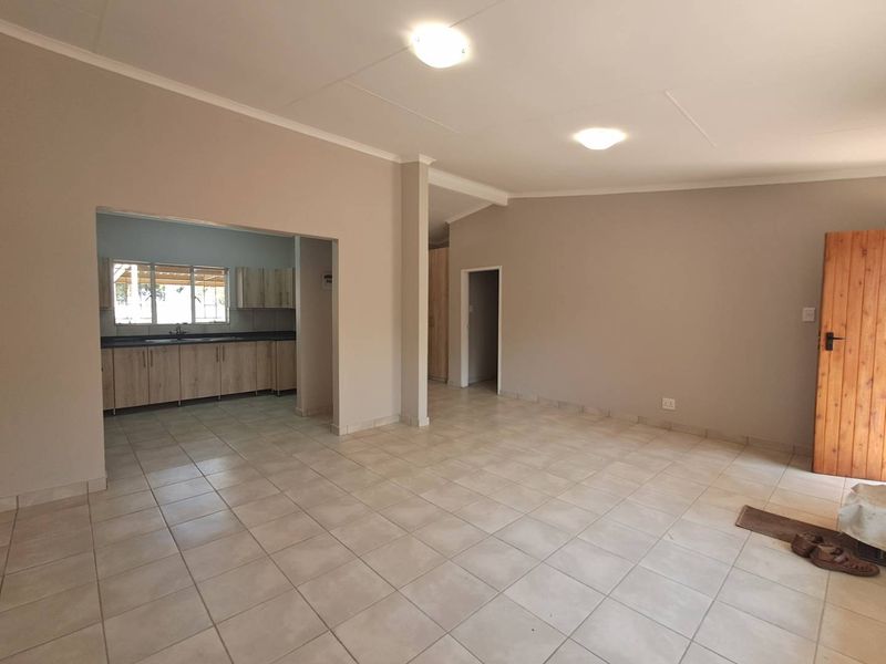 Spacious open-plan living area featuring neutral tiled flooring and a connected kitchen with modern cabinetry and ample counter space.