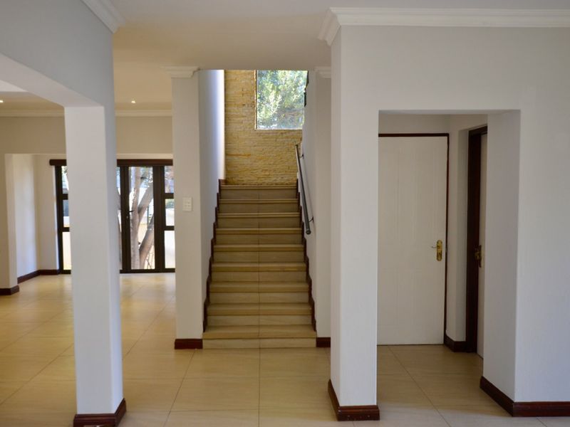 Spacious entrance hallway featuring tiled flooring, a central staircase with a stone feature wall, and access to adjacent living areas.