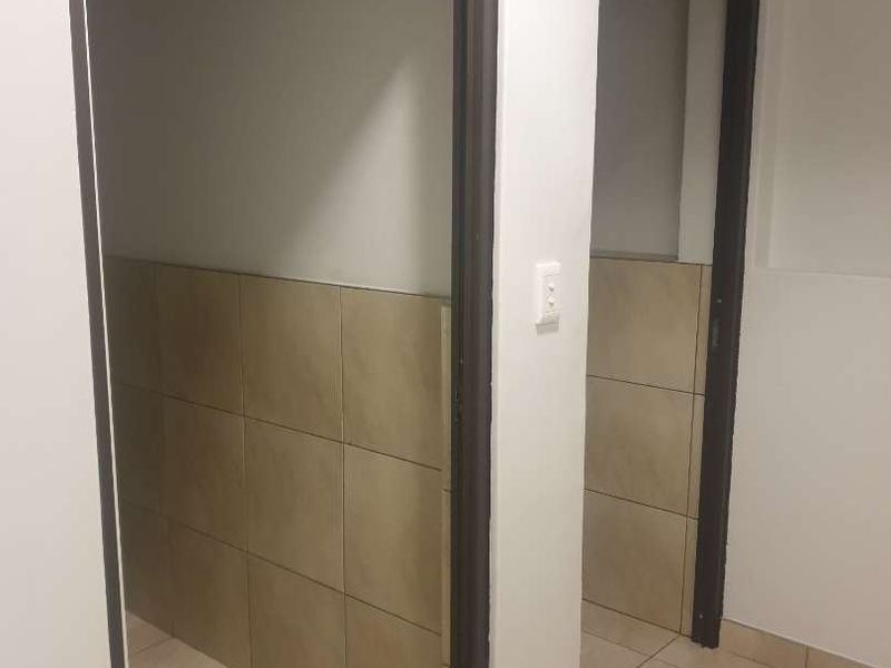 A functional hallway area featuring neutral floor tiles and half-height wall tiling, providing a clean and durable transition space.
