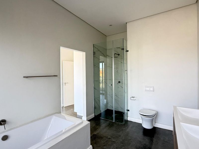 Modern bathroom featuring a built-in bathtub, glass-enclosed shower, wall-mounted toilet, and a double vanity with contemporary fixtures.
