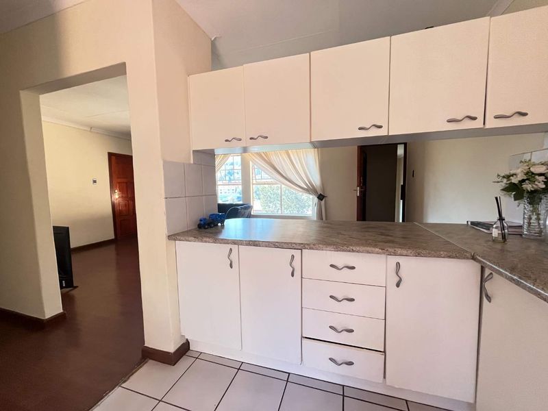 A functional kitchen area featuring white cabinetry, laminate countertops, and tiled flooring, offering a clean and practical layout for daily use.