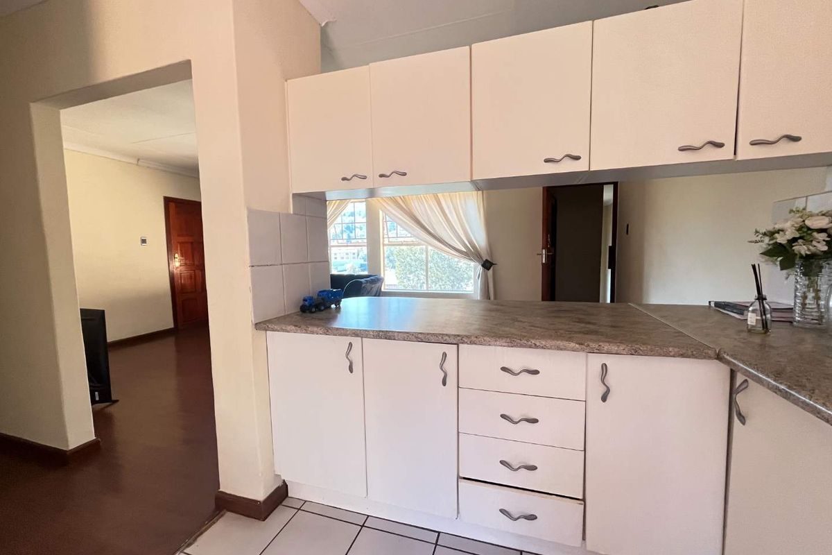 A functional kitchen area featuring white cabinetry, laminate countertops, and tiled flooring, offering a clean and practical layout for daily use.