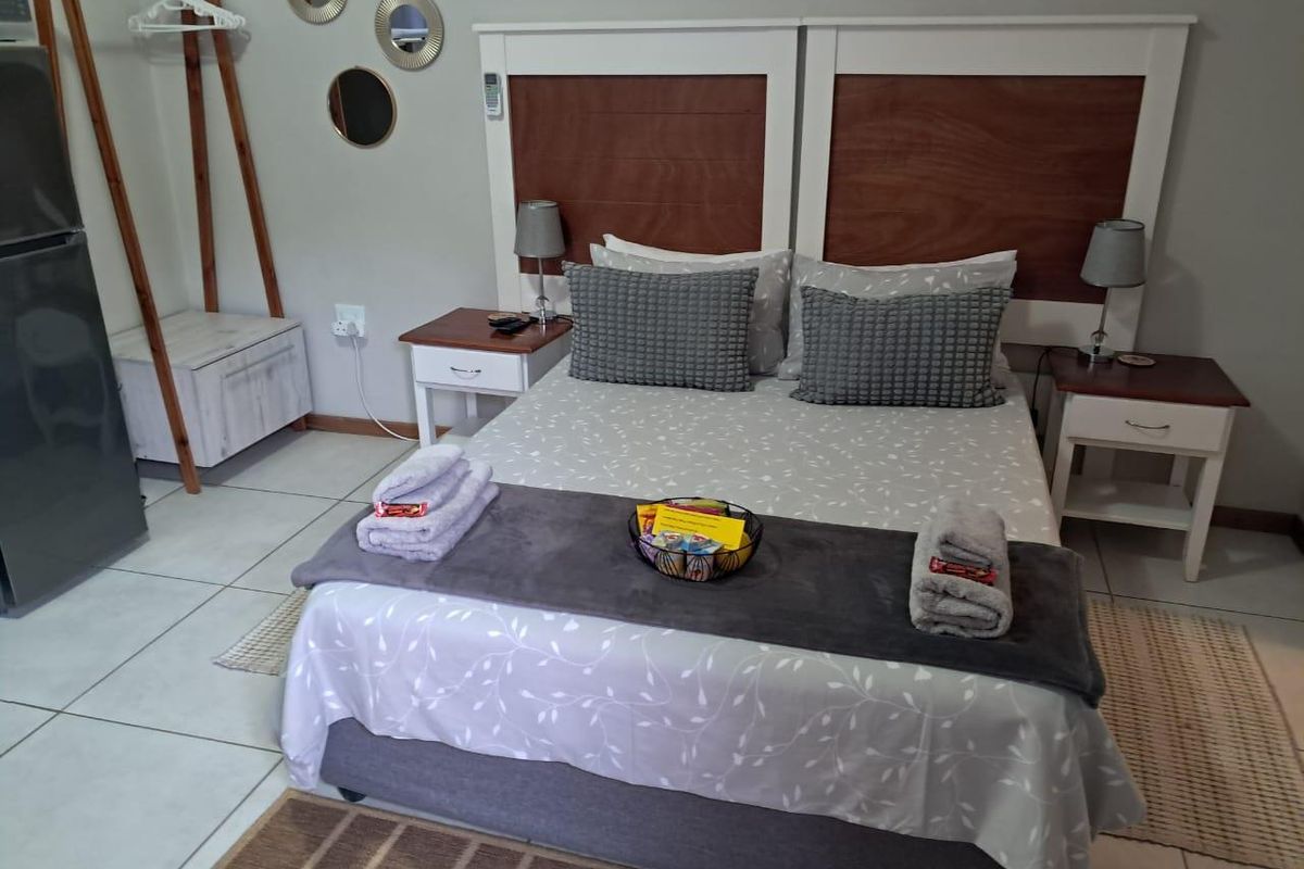 A well-maintained bedroom featuring tiled flooring and a custom built-in wooden headboard, providing a clean and functional guest accommodation space.