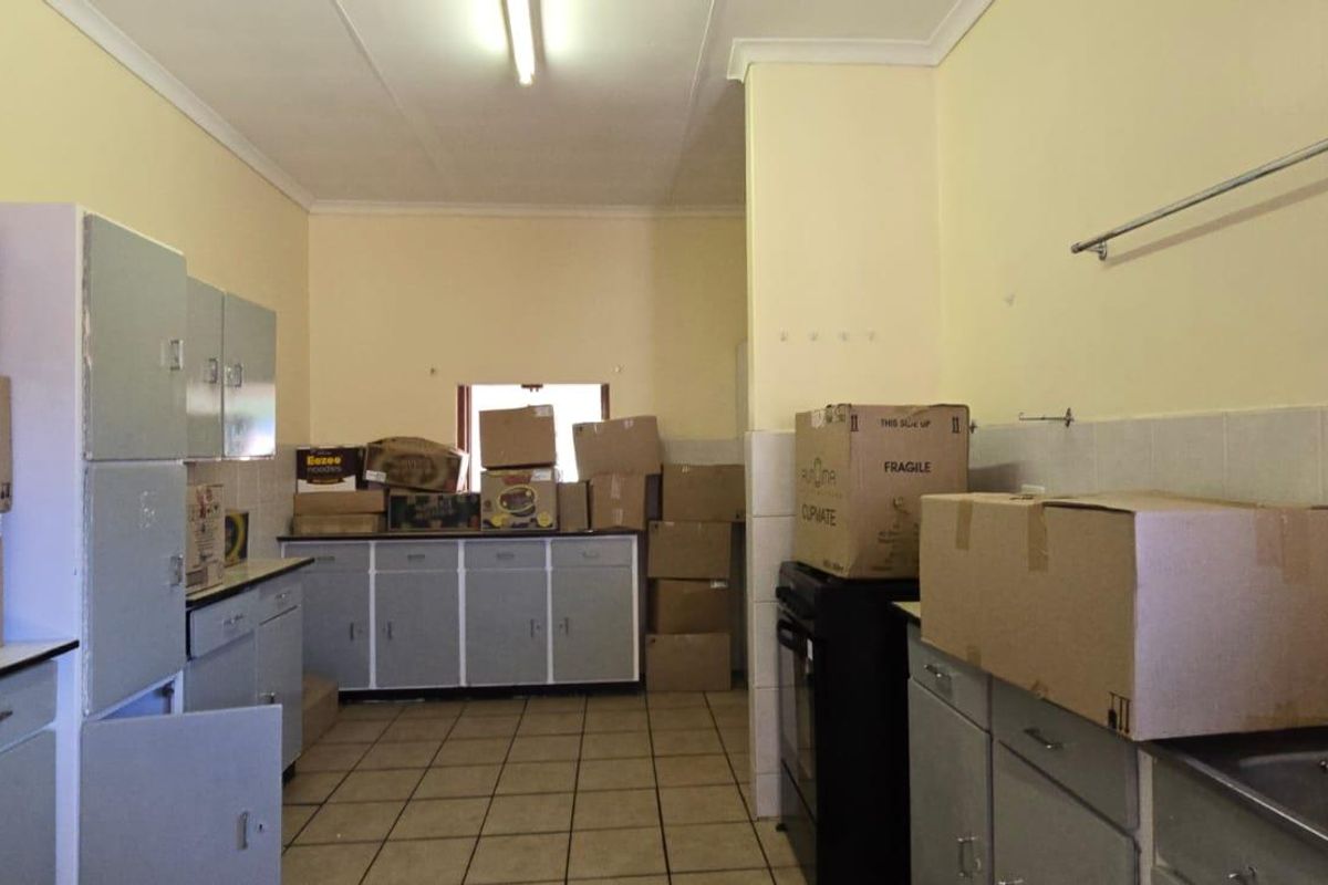 A functional kitchen space featuring tiled flooring, built-in cabinetry, and a stainless steel sink, offering potential for modernization and renovation.