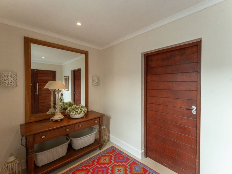A welcoming entrance hall featuring a solid timber door, recessed downlighting, and clean neutral finishes.