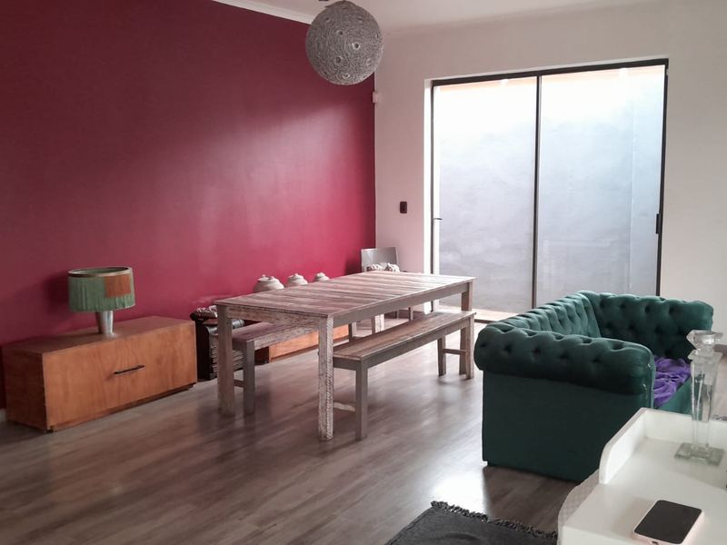 Spacious open-plan living and dining area featuring laminate flooring and a large sliding glass door providing access to the exterior.