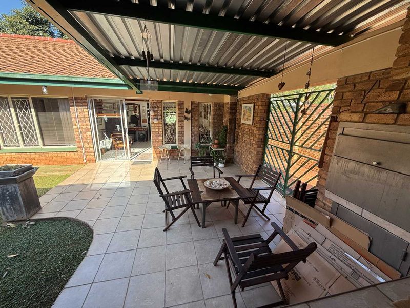Covered outdoor patio featuring a built-in brick fireplace, tiled flooring, and direct access to the home through sliding glass doors.