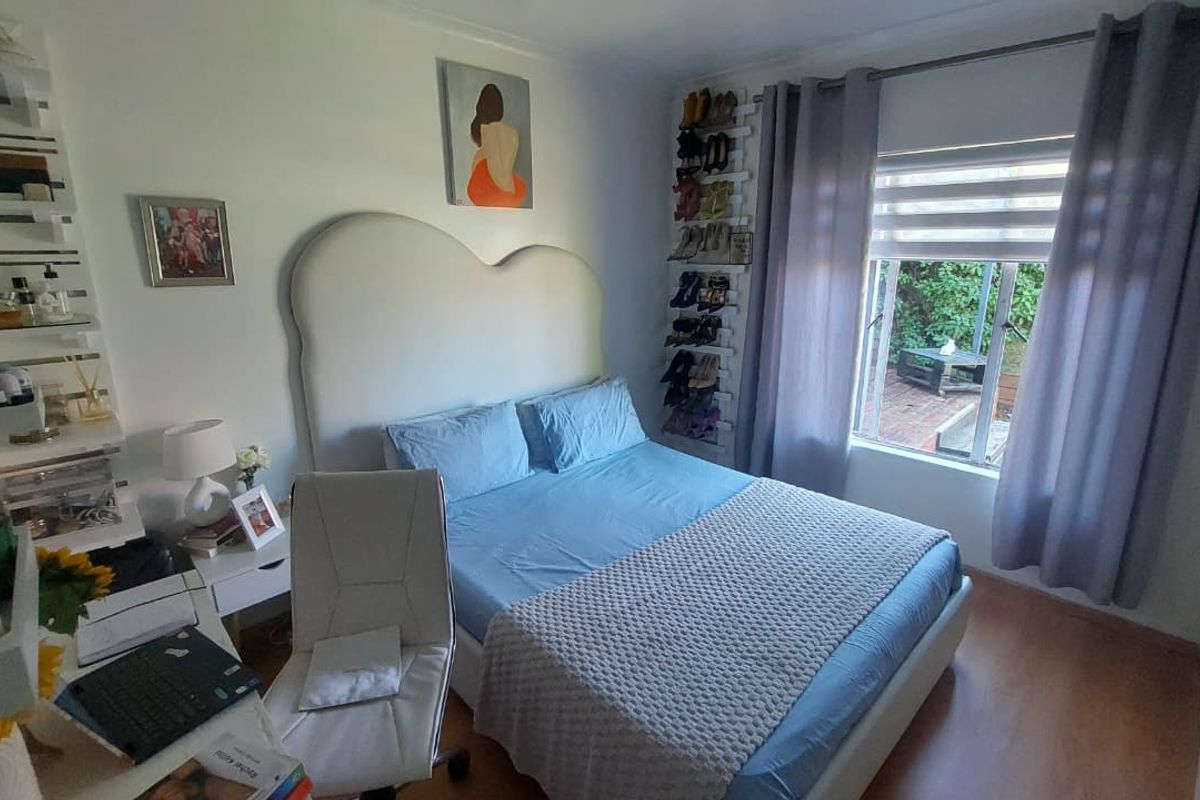 A cozy bedroom featuring laminate flooring, a window with blinds, and built-in shelving, offering a functional and comfortable living space.