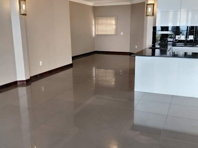 Spacious open-plan living area featuring polished porcelain tiles, modern kitchen with granite countertops, and recessed lighting throughout.