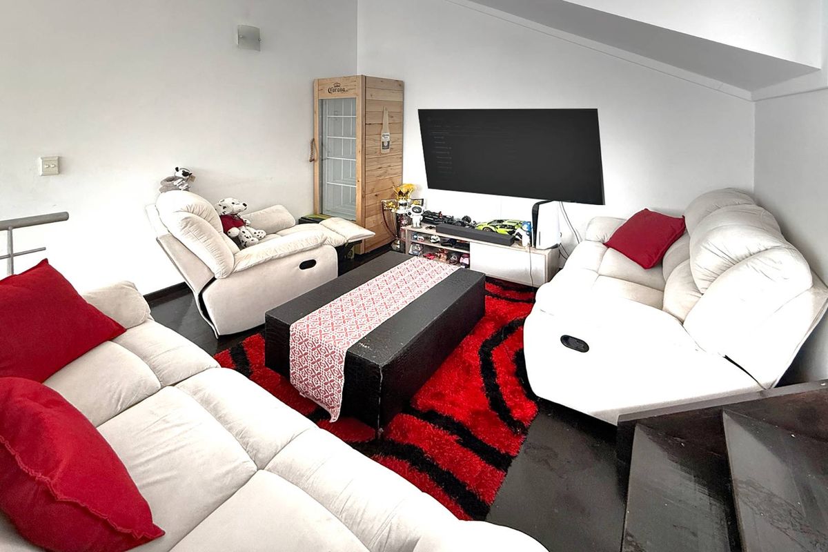 A living room area featuring dark flooring and a sloped ceiling, providing a cozy space for relaxation and entertainment.