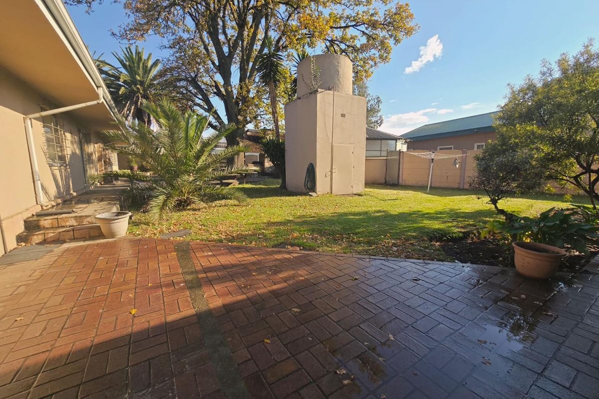 A spacious rear garden featuring a brick-paved patio area, a lawn, and a prominent water tank tower structure.