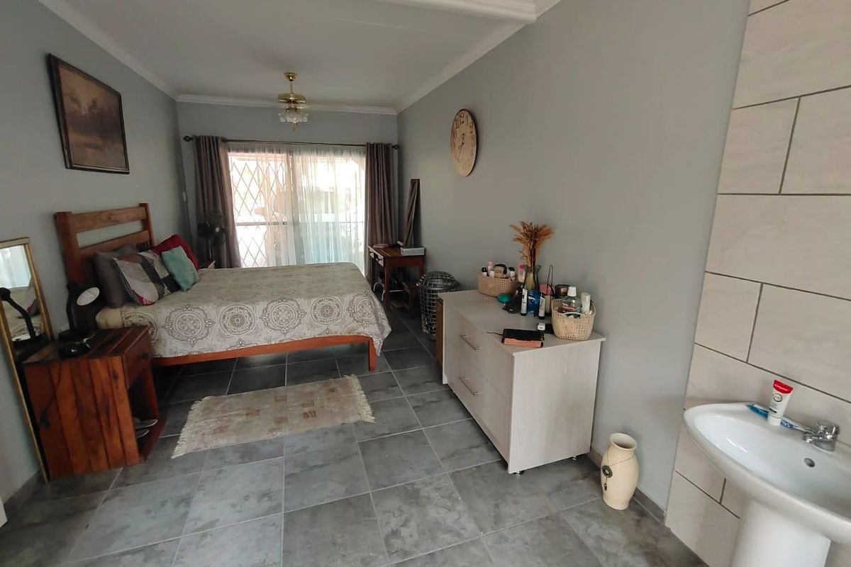 A bedroom featuring tiled flooring, a pedestal basin, and sliding glass doors leading to an outdoor area.