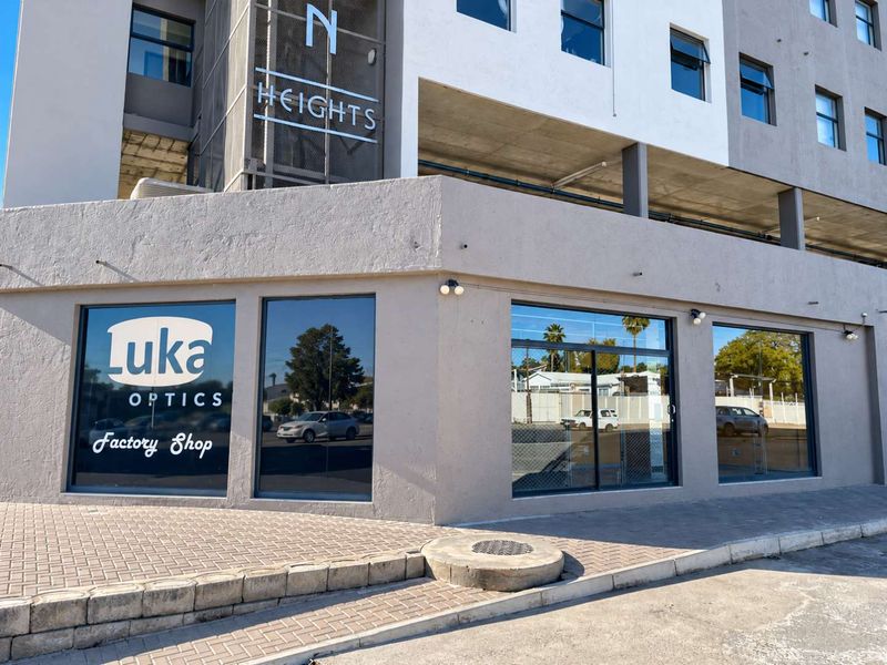 Street-level retail storefront featuring large display windows, modern signage, and paved sidewalk access in a multi-story commercial building.