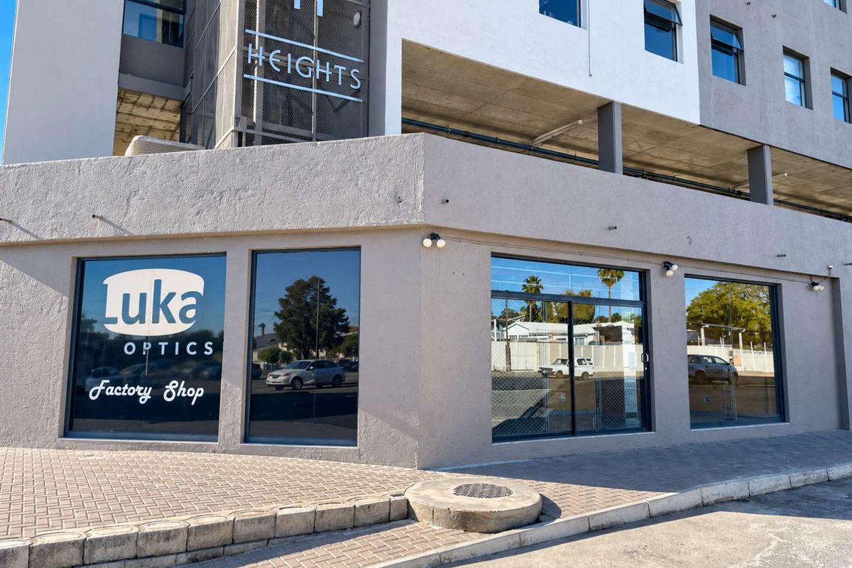 Street-level retail storefront featuring large display windows, modern signage, and paved sidewalk access in a multi-story commercial building.