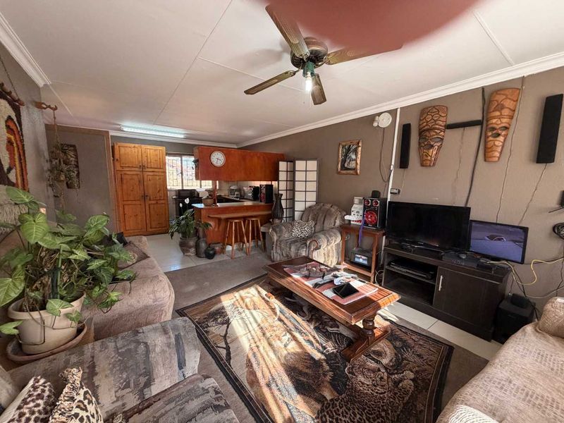 Open-plan living area featuring a breakfast counter, kitchen cabinetry, and ceiling fan, providing a functional layout for daily living.