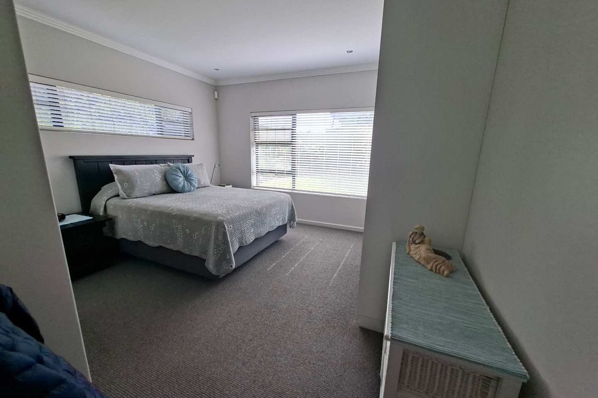 A well-maintained bedroom featuring neutral carpeting, cove cornicing, and venetian blinds, providing a bright and comfortable living space.