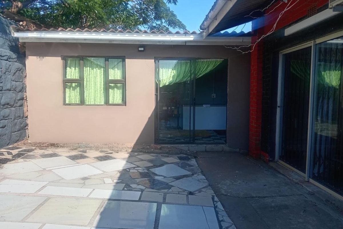 Rear exterior view of the property featuring a paved patio area, sliding glass doors, and access to the main dwelling.