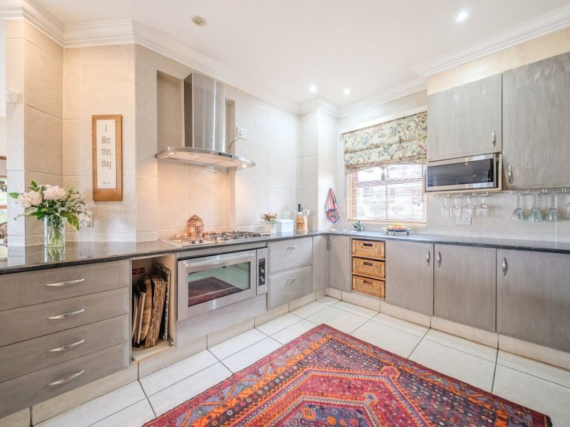 A well-appointed kitchen featuring modern grey cabinetry, granite countertops, built-in stainless steel appliances, and tiled flooring with recessed lighting.