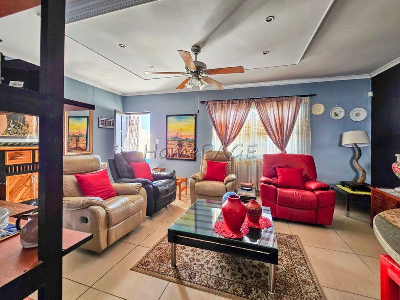 A living room featuring tiled flooring, a ceiling fan, and recessed lighting with decorative cove molding.
