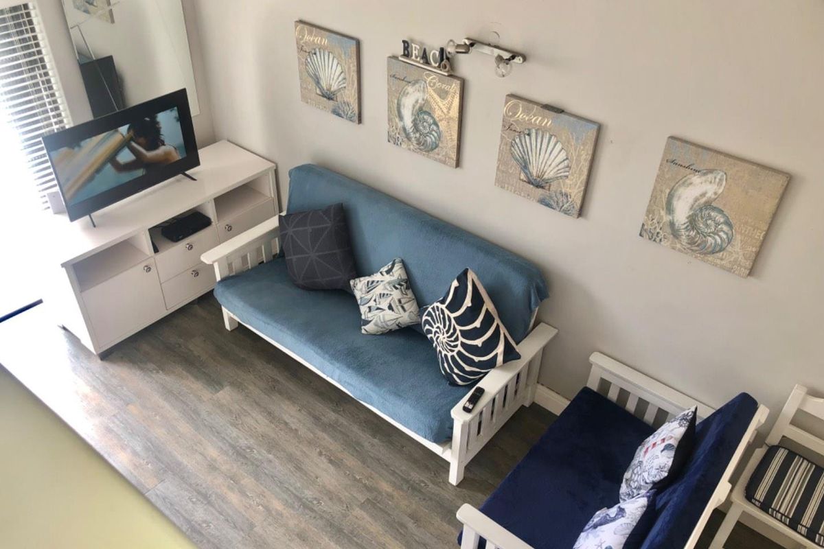 A compact living area featuring wood-look laminate flooring and neutral wall tones, providing a functional space for relaxation.