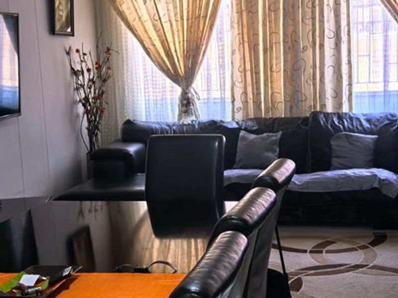 Open plan living and dining area featuring tiled flooring and large windows with curtain treatments.