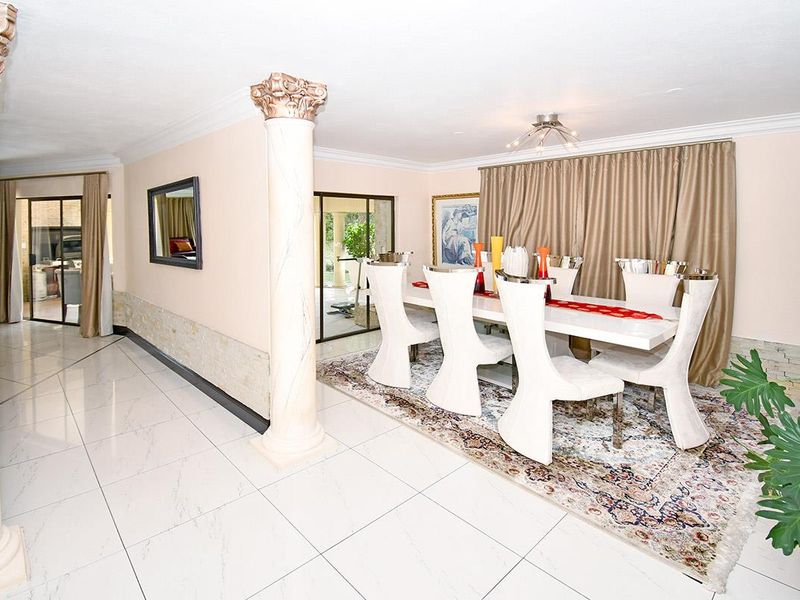 Spacious dining area featuring polished porcelain floor tiles, decorative columns, and stone wall accents, with direct access to the outdoor patio through sliding glass doors.