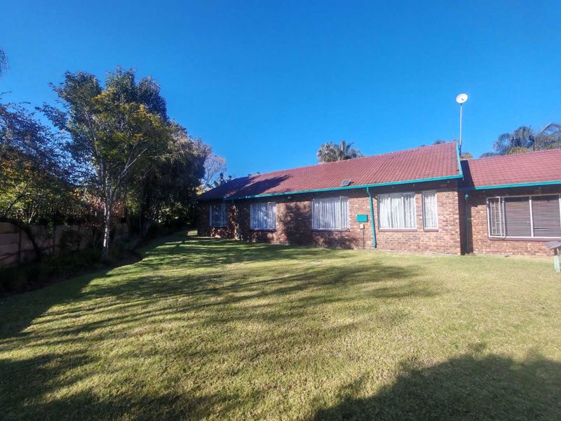 A view of the rear exterior of the house featuring a brick facade, tiled roof, and a spacious lawn area.