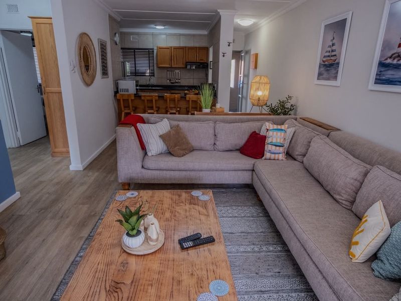 Open-plan living area featuring laminate flooring and a functional kitchen with granite countertops and built-in cabinetry.